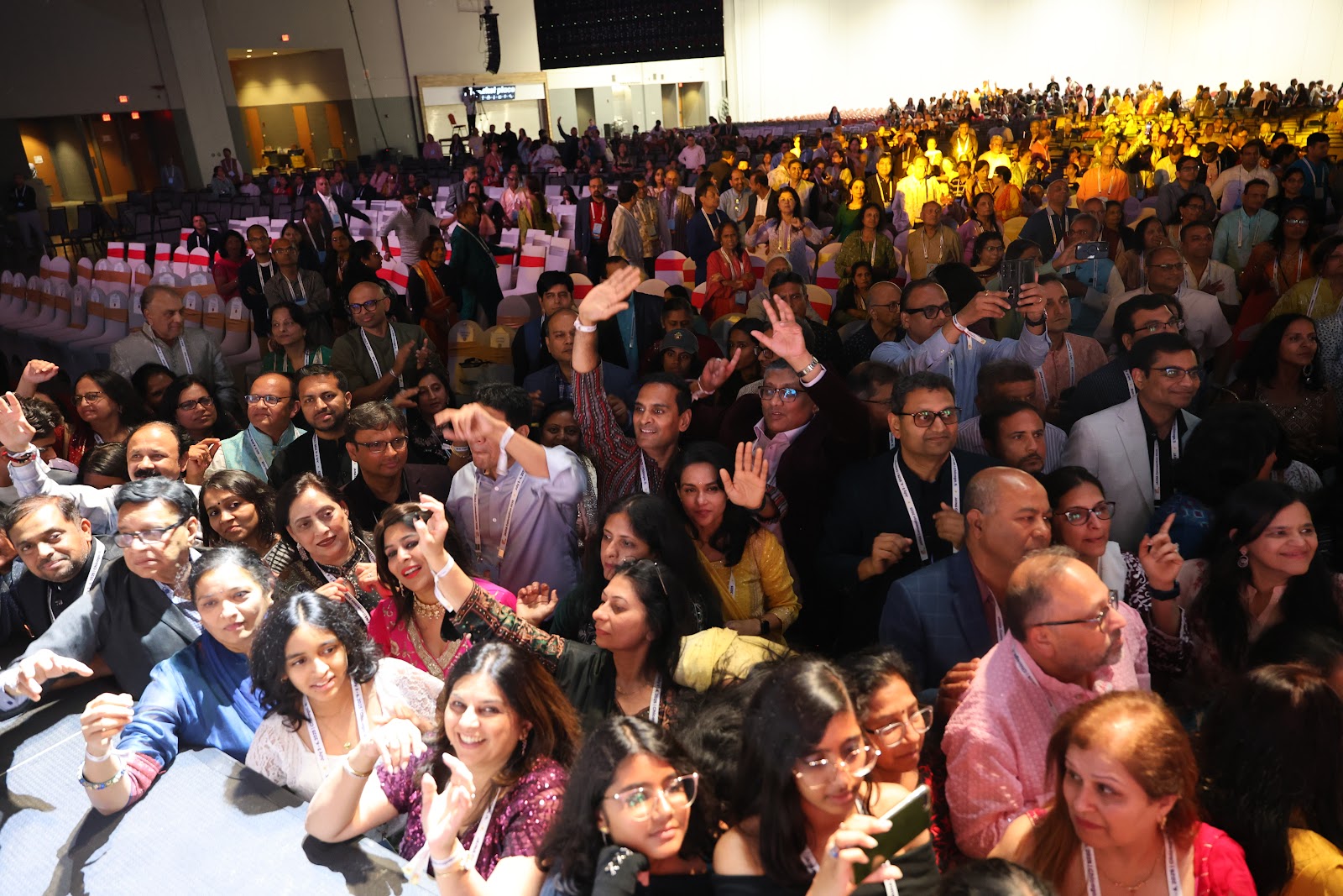 A packed convention hall, hands in the air